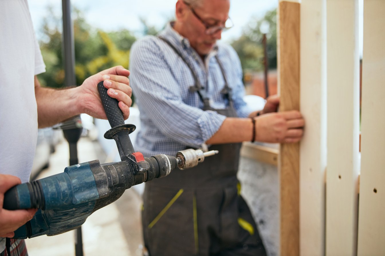Two manual workers installing a wooden fence